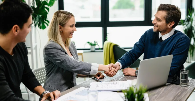 young-happy-couple-meeting-with-financial-advisor-office-woman-is-handshaking-with-agent 1 - Finney Insurance Corporation A Young Lady Greeting With her Young Co Worker In An Insurance Office